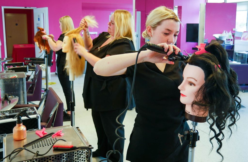 Three lecturers at Brecon Beacons Colleges cutting hair on hair models in a salon.