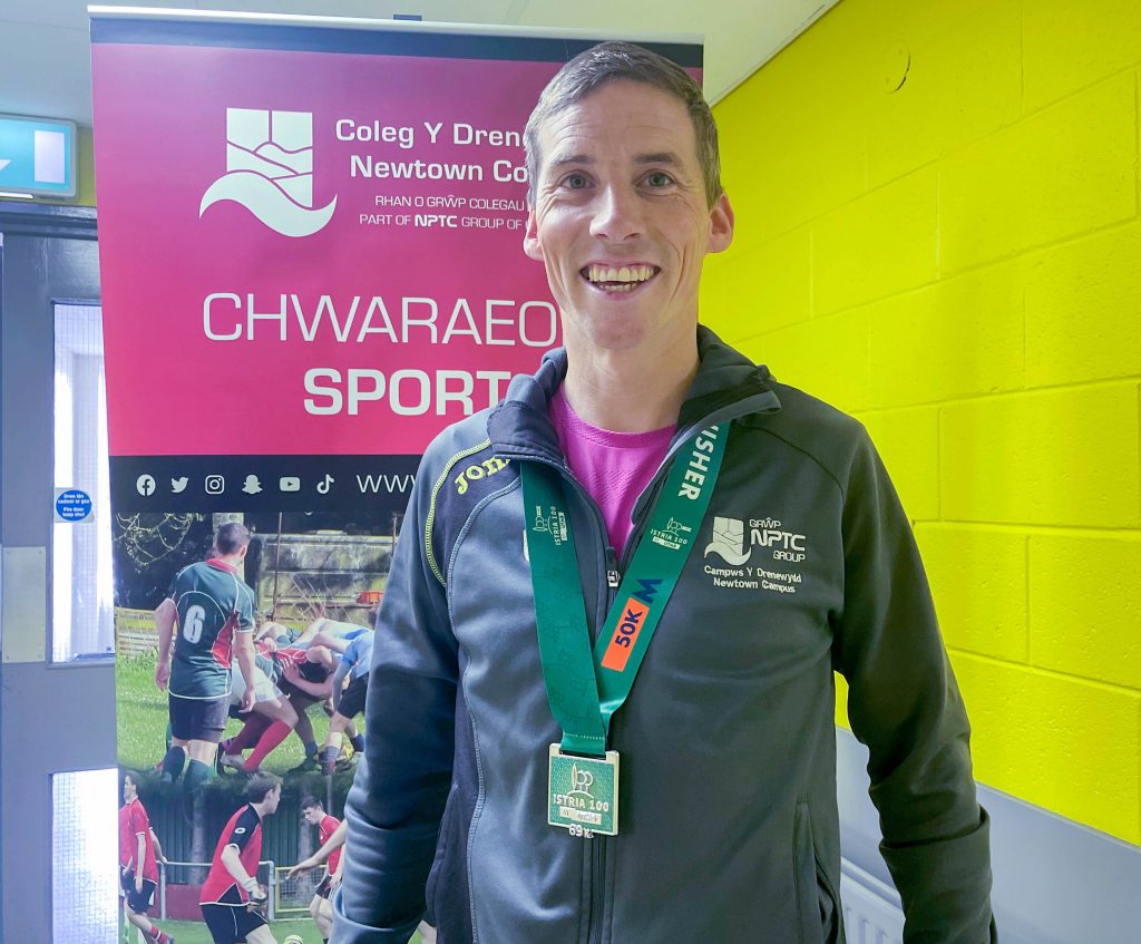 Sport lecturer Andy Davies with a 50k running medal around his neck.