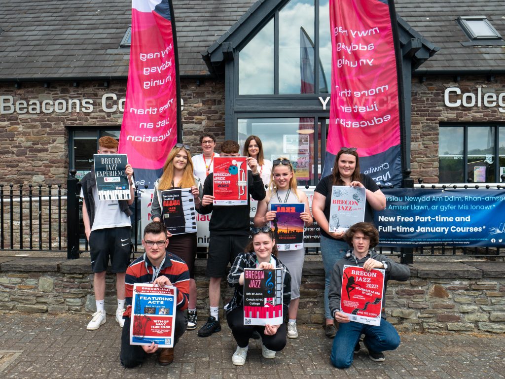 Students outside The Cwtch - Brecon Beacons College holding up Brecon Jazz Festival posters.