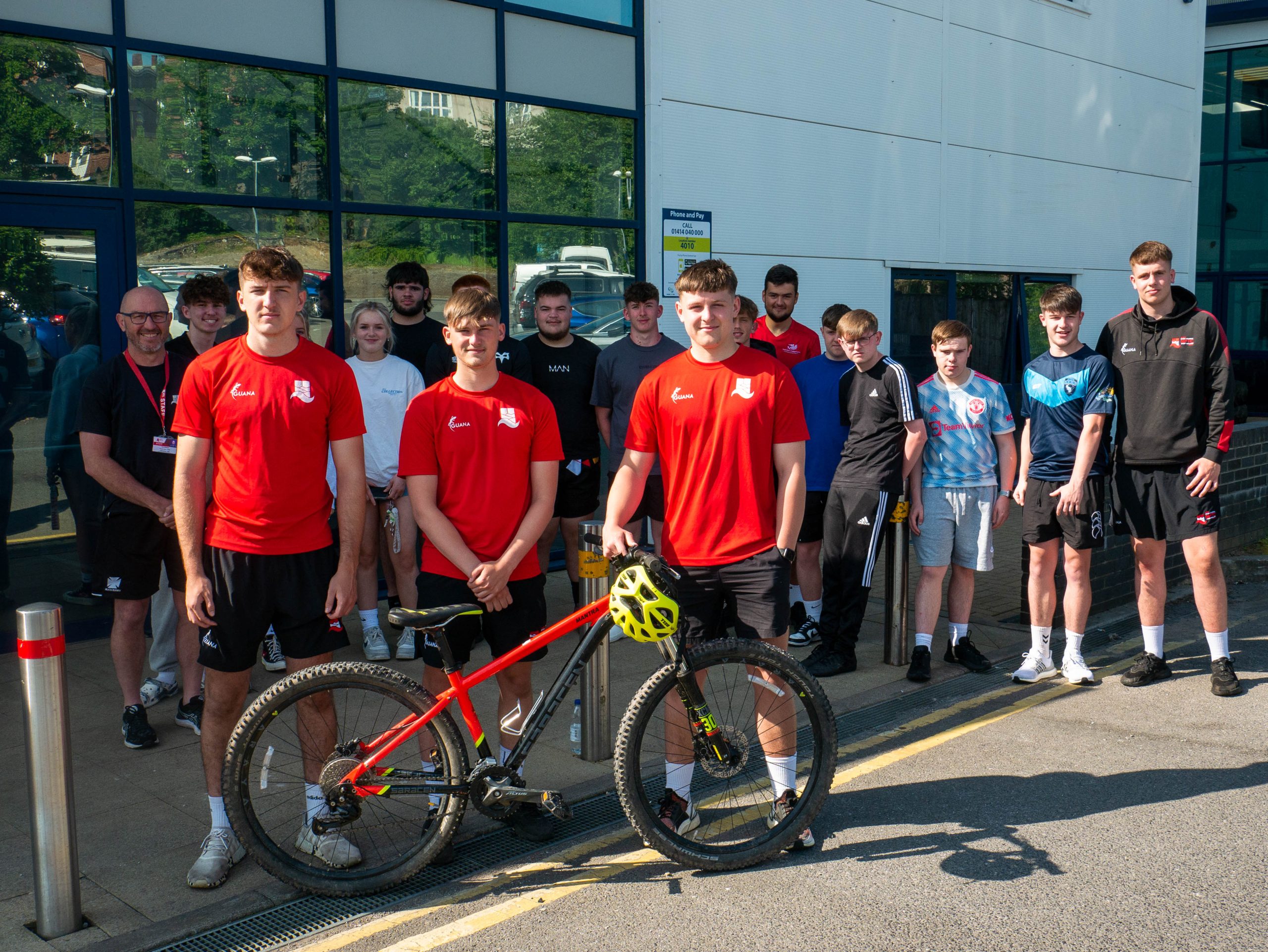 Group of Llanadarcy Academy of Sports students standing outside with a bike.