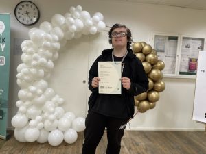 Student Thomas with his certifcate and balloons at Netwown College.