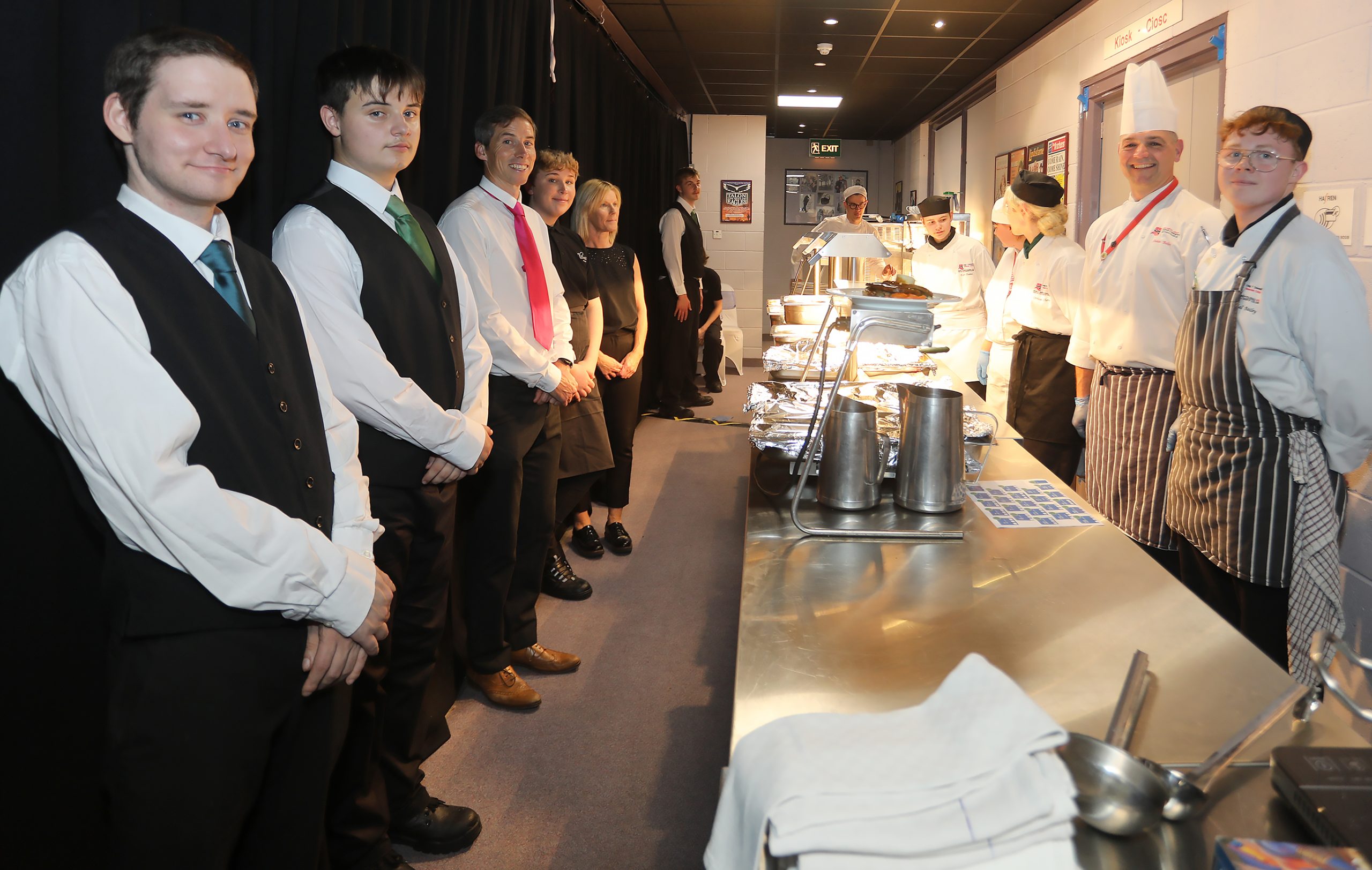 Catering & Hospitality students at Newtown College dressed formally, standing in line ready to serve guests at the Powys Business Awards