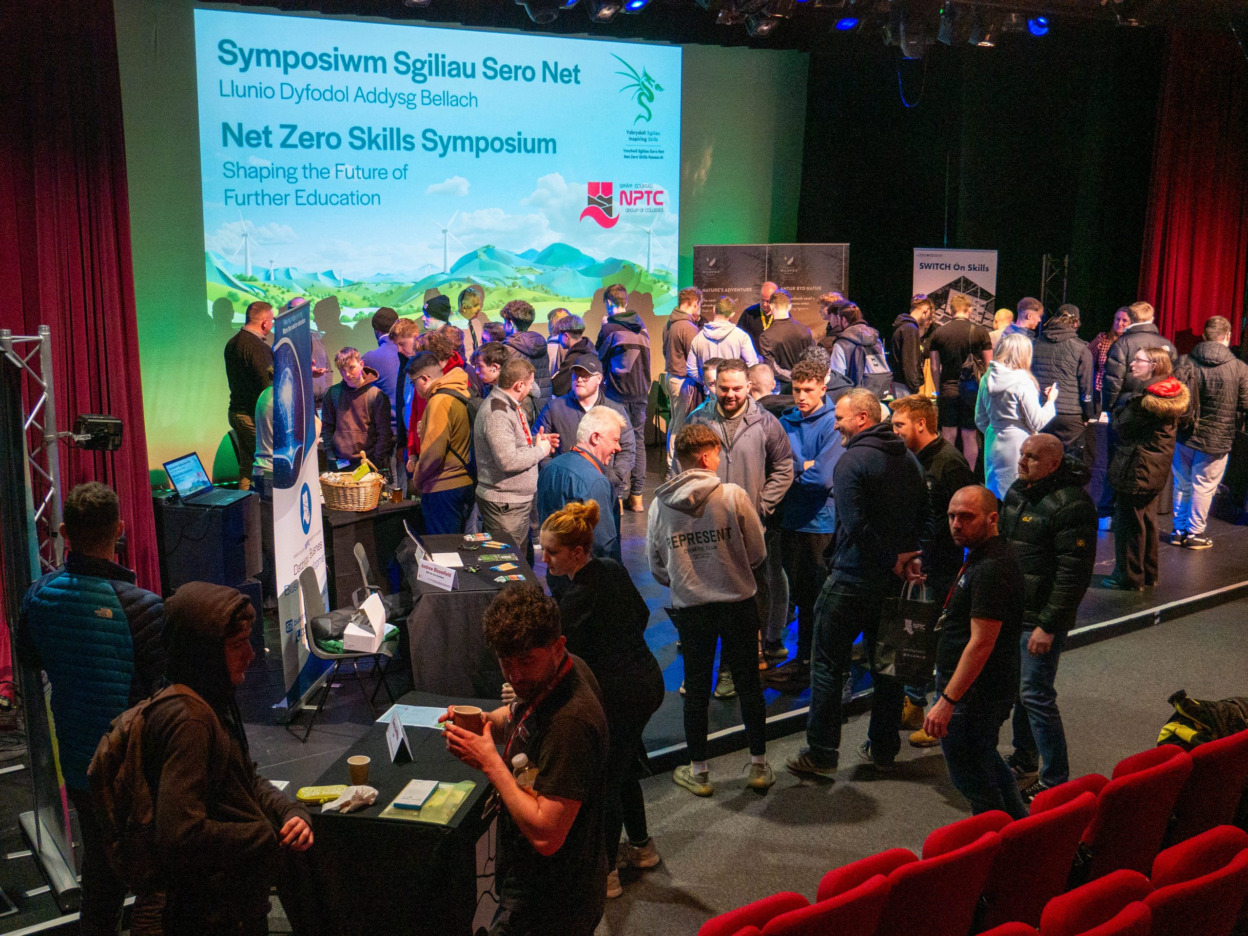 Net Zero Skills Symposium event with pop up stands and guests networking and chatting at the Nidum Theatre.