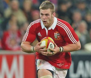 Rugby player Dan Lydiate in British and Irish Lions kit running with the ball.